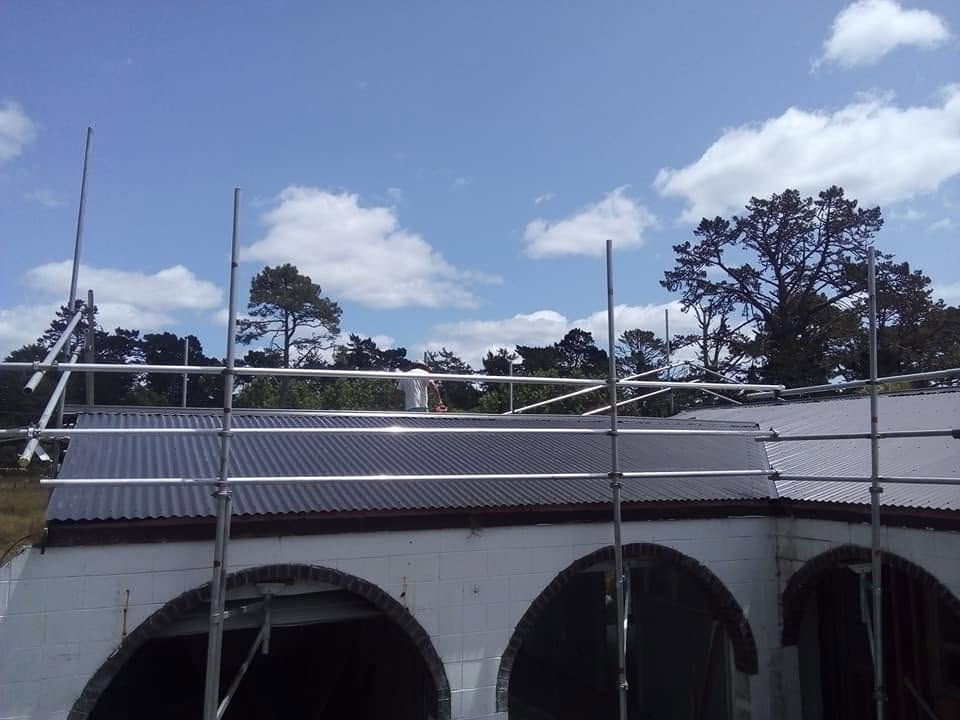 Scaffolded arched villa mid re-roof under a blue sky